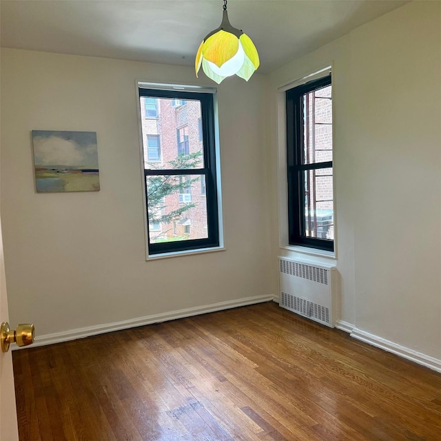 83-20 98th St Unit 1H, Woodhaven, NY 11421 - empty room featuring radiator heating unit, wood finished floors, and plenty of natural light