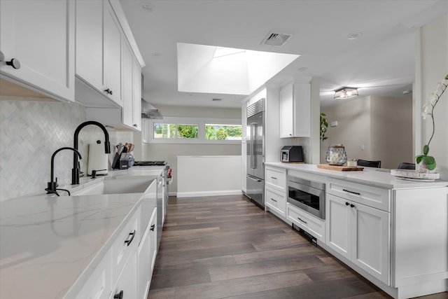 2854 Lenox Rd, Oceanside, NY 11572 - kitchen featuring built in appliances, a skylight, backsplash, dark wood-type flooring, and white cabinetry