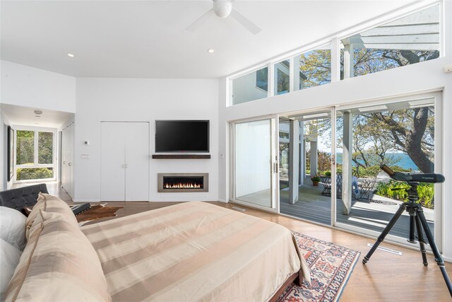 4105 Soundview Ave, Mattituck, NY 11952 - bedroom featuring access to outside, a warm lit fireplace, wood finished floors, a towering ceiling, and recessed lighting