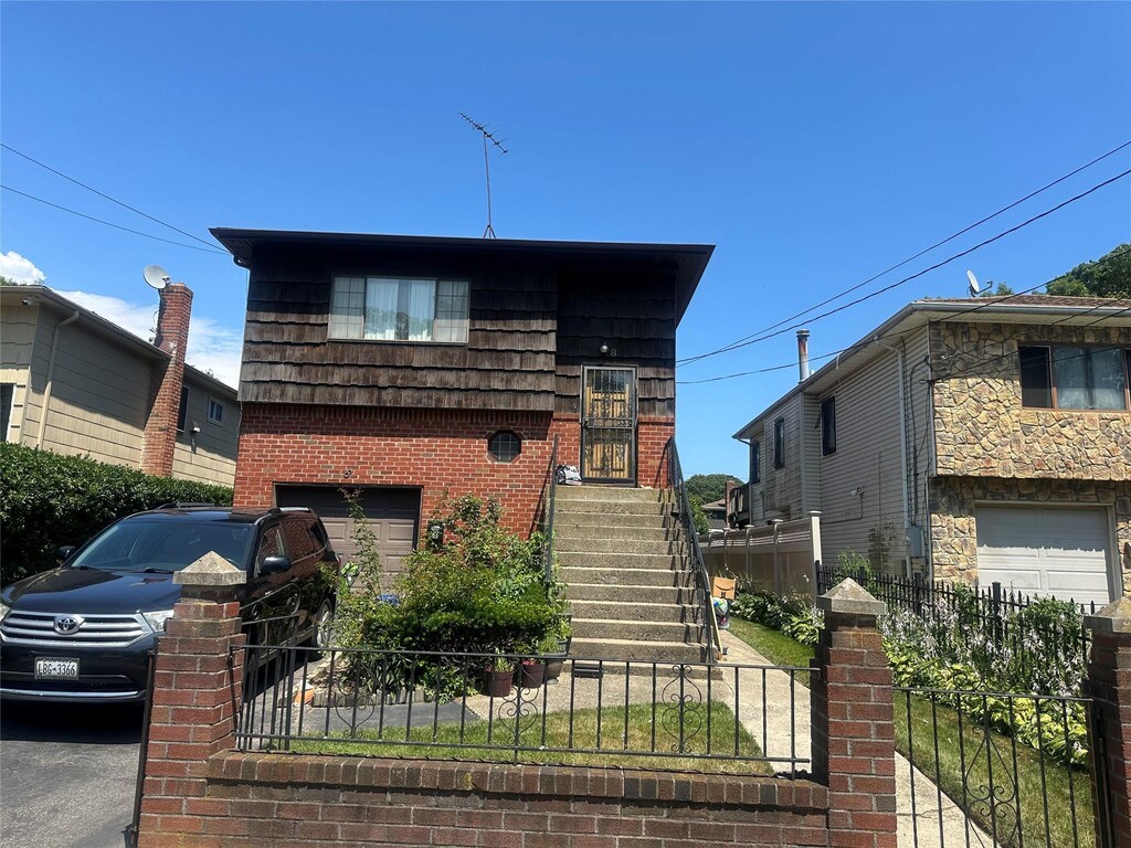 8 Bainbridge St, Roosevelt, NY 11575 - tri-level home with an attached garage and brick siding