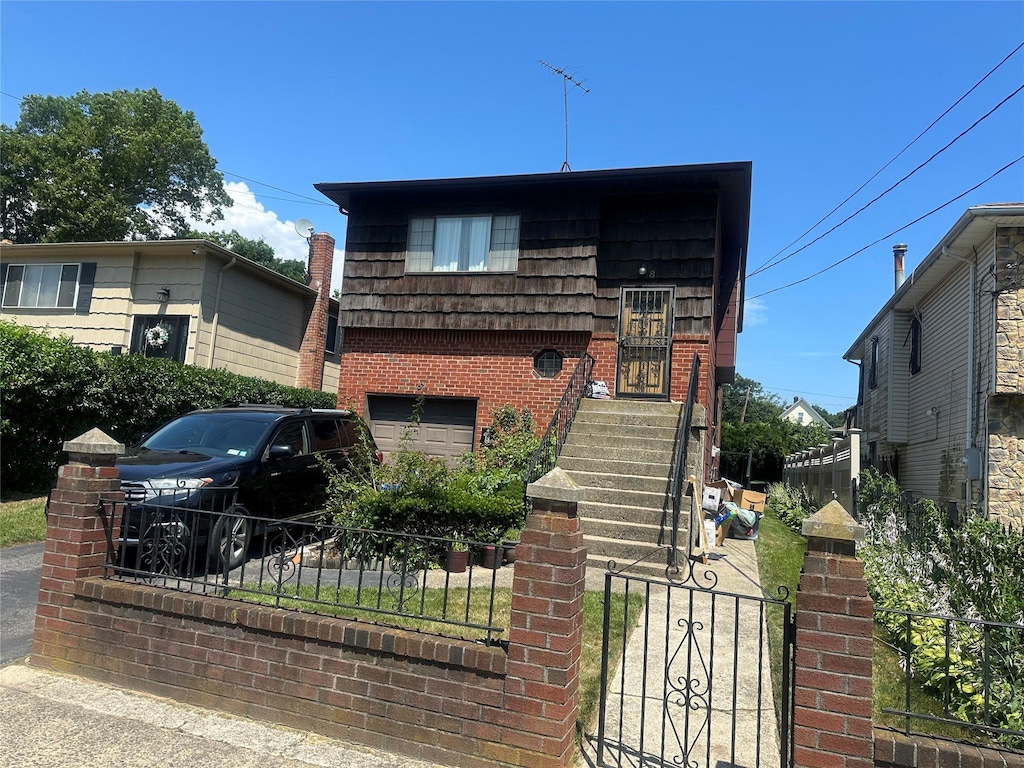 8 Bainbridge St, Roosevelt, NY 11575 - view of front facade with a garage, a fenced front yard, and brick siding