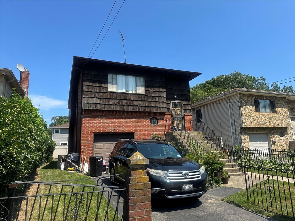 8 Bainbridge St, Roosevelt, NY 11575 - tri-level home with a garage, brick siding, and stairs