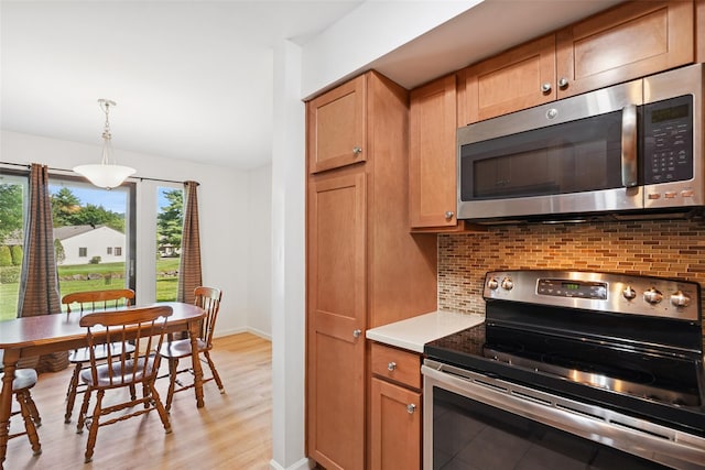 52 Jefferson Oval Unit E, Yorktown Heights, NY 10598 - kitchen featuring appliances with stainless steel finishes, decorative backsplash, light wood-style floors, and light countertops