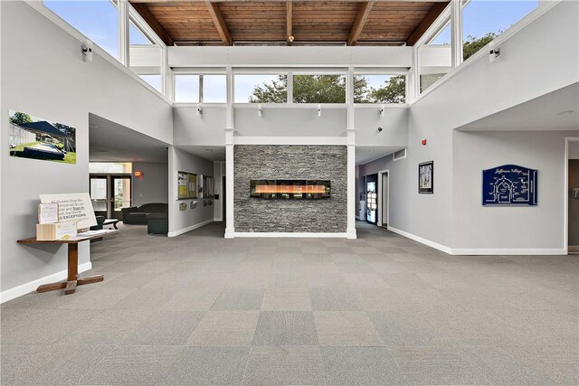 52 Jefferson Oval Unit E, Yorktown Heights, NY 10598 - unfurnished living room with a towering ceiling, a wood ceiling with exposed beams, carpet, and a fireplace