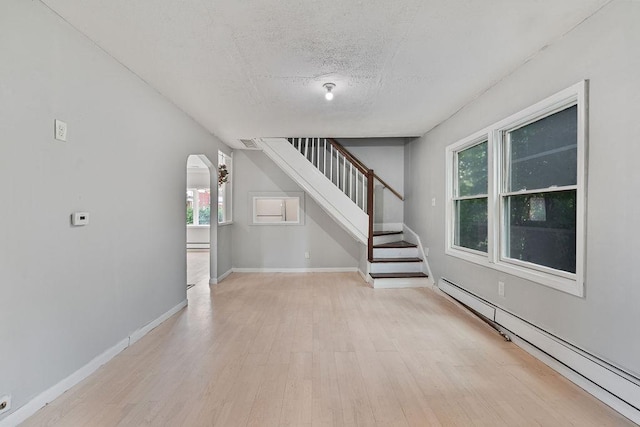14 Cooper Dr, Nanuet, NY 10954 - unfurnished living room with a baseboard radiator, stairway, light wood-type flooring, and a textured ceiling