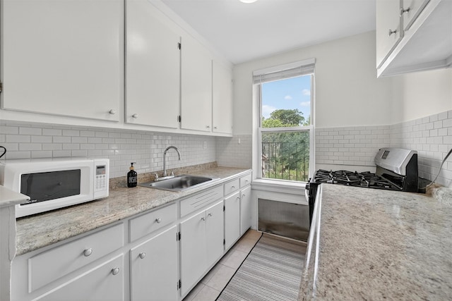 4295 Webster Ave Unit 5J, Bronx, NY 10470 - kitchen with white microwave, gas stove, white cabinets, light countertops, and decorative backsplash