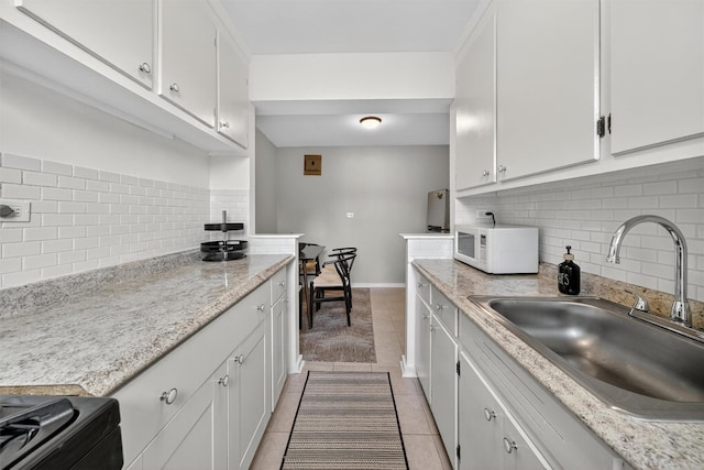 4295 Webster Ave Unit 5J, Bronx, NY 10470 - kitchen with white microwave, tasteful backsplash, black range with electric cooktop, white cabinets, and light tile patterned floors
