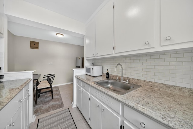 4295 Webster Ave Unit 5J, Bronx, NY 10470 - kitchen featuring white microwave, light tile patterned floors, decorative backsplash, and white cabinets