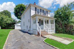 10 Valentine St, Glen Cove, NY 11542 - american foursquare style home with a porch, a front lawn, an outdoor structure, and a garage