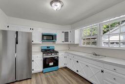 10 Valentine St, Glen Cove, NY 11542 - kitchen with appliances with stainless steel finishes, dark wood-style floors, light countertops, and white cabinetry