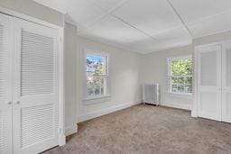 10 Valentine St, Glen Cove, NY 11542 - unfurnished bedroom with radiator, multiple windows, and carpet flooring
