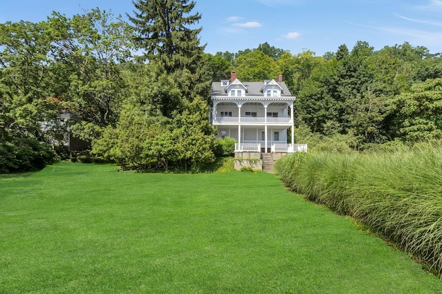 165 River Rd, Nyack, NY 10960 - view of grassy yard featuring a balcony, covered porch, and a wooded view