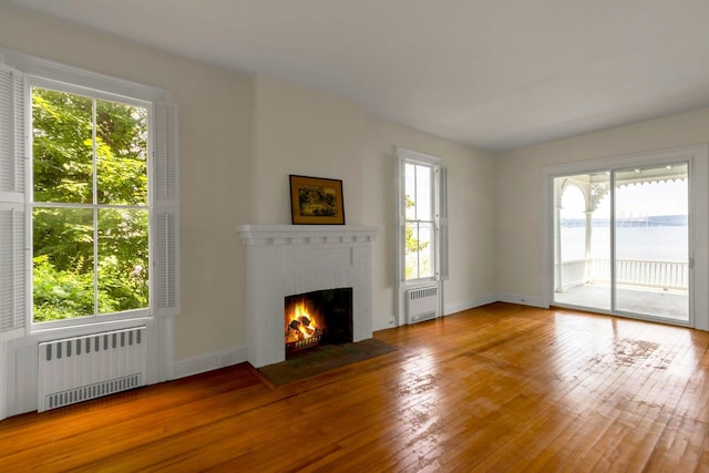 165 River Rd, Nyack, NY 10960 - unfurnished living room featuring radiator, a brick fireplace, and hardwood / wood-style flooring