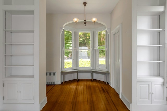 165 River Rd, Nyack, NY 10960 - unfurnished dining area featuring radiator, arched walkways, dark wood-style flooring, built in features, and a chandelier
