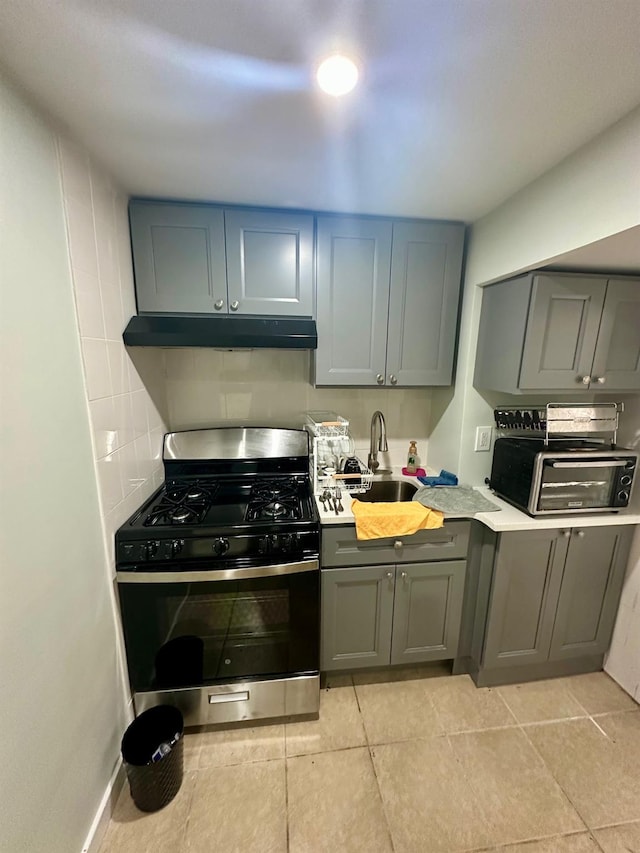 153-15 79th Ave, Flushing, NY 11367 - kitchen with stainless steel range with gas stovetop, under cabinet range hood, gray cabinets, light countertops, and light tile patterned flooring