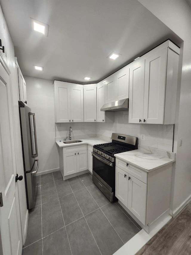 167 Euclid Ave, Brooklyn, NY 11208 - kitchen with stainless steel appliances, under cabinet range hood, white cabinets, dark tile patterned floors, and backsplash