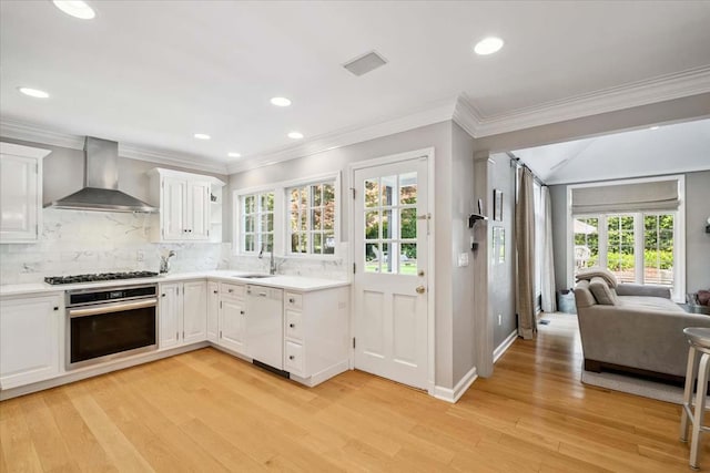 7 Westview Ln, Scarsdale, NY 10583 - kitchen featuring appliances with stainless steel finishes, wall chimney range hood, light wood-style flooring, open floor plan, and backsplash