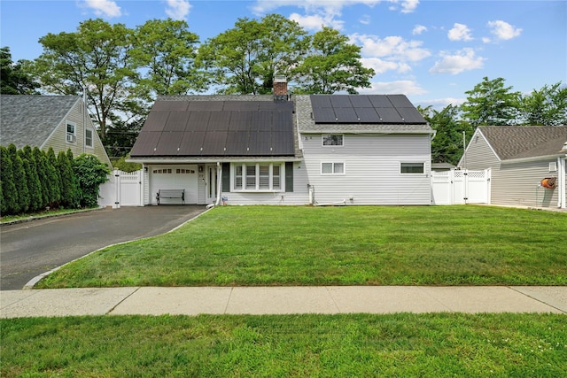 24 Border Ln, Levittown, NY 11756 - view of front facade with a gate, roof mounted solar panels, an attached garage, driveway, and a chimney