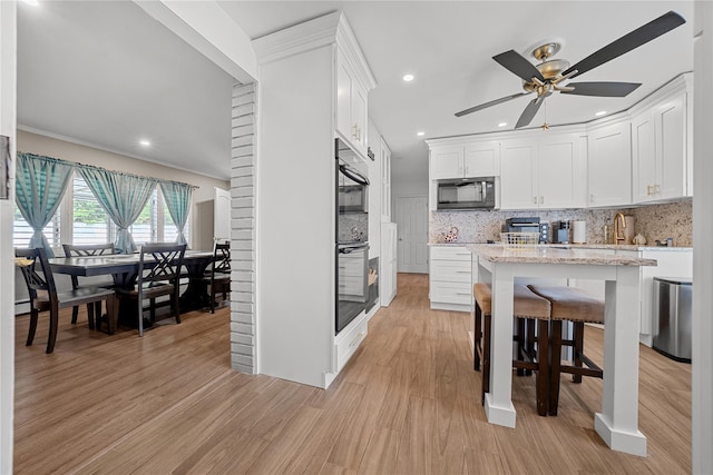 24 Border Ln, Levittown, NY 11756 - kitchen with stainless steel microwave, light wood finished floors, white cabinets, decorative backsplash, and recessed lighting