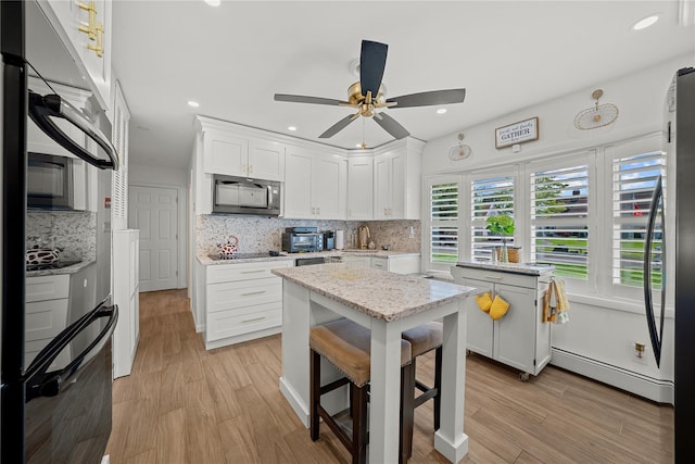 24 Border Ln, Levittown, NY 11756 - kitchen with black appliances, tasteful backsplash, ceiling fan, white cabinets, and light wood finished floors