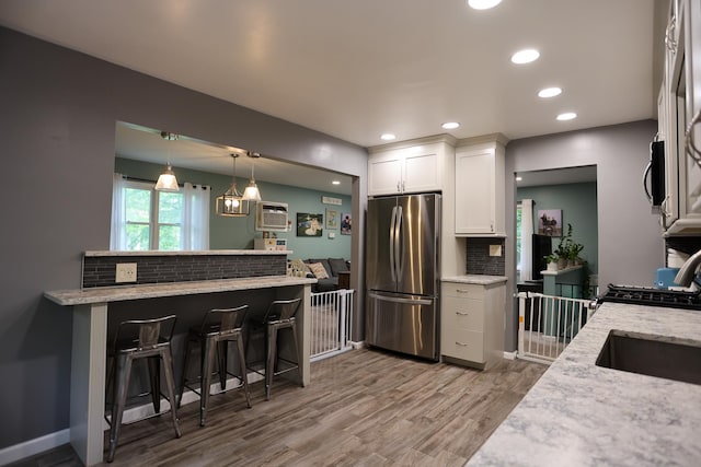 21 Edgebrook Ln, Airmont, NY 10952 - kitchen with appliances with stainless steel finishes, backsplash, a kitchen breakfast bar, white cabinetry, and wood finished floors
