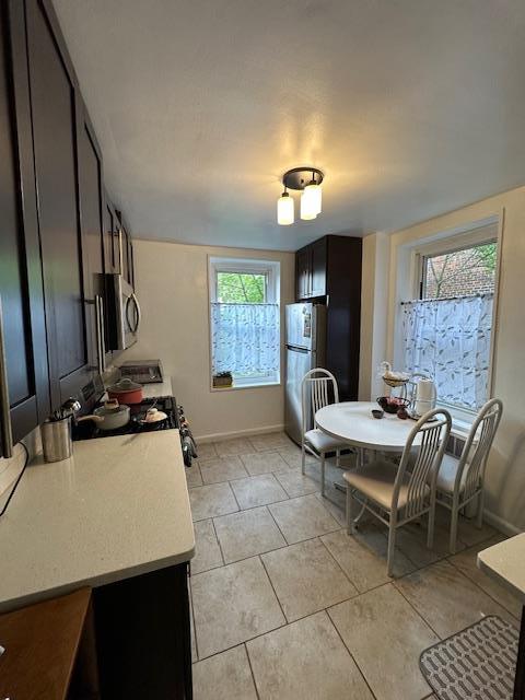 18-65 211th St Unit 5D, Bayside, NY 11360 - kitchen with stainless steel microwave, freestanding refrigerator, light countertops, range, and light tile patterned floors