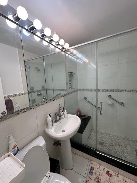 18-65 211th St Unit 5D, Bayside, NY 11360 - full bathroom with a stall shower, tile patterned flooring, and tile walls