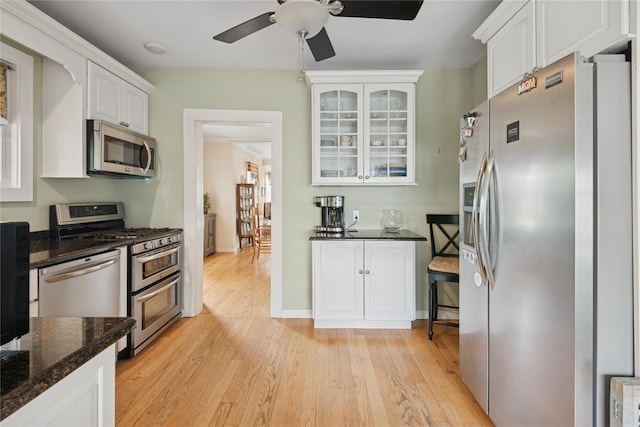 111 Little E Neck Rd, Babylon, NY 11702 - kitchen featuring stainless steel appliances, white cabinetry, light wood-type flooring, glass insert cabinets, and dark stone countertops