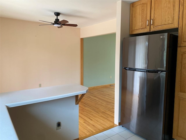 14 Shepard Rd, Warwick, NY 10990 - kitchen with freestanding refrigerator, a ceiling fan, brown cabinets, light tile patterned flooring, and light countertops