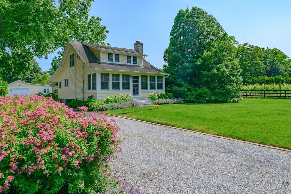 9780 Old Sound Ave, Mattituck, NY 11952 - view of front of house with a chimney, an outdoor structure, gravel driveway, and a detached garage