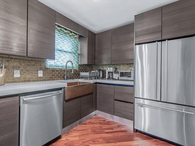 165-05 67th Ave, Fresh Meadows, NY 11365 - kitchen with appliances with stainless steel finishes, modern cabinets, decorative backsplash, dark brown cabinetry, and light countertops