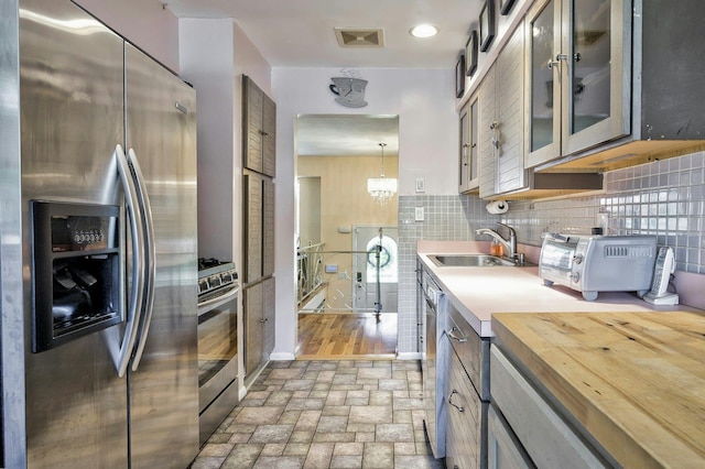 26 Comanche, Commack, NY 11725 - kitchen with appliances with stainless steel finishes, brick patterned flooring, glass insert cabinets, wood counters, and tasteful backsplash