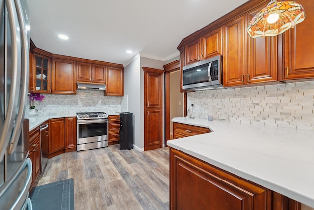 30 Birchwood Ter, Nanuet, NY 10954 - kitchen with stainless steel appliances, under cabinet range hood, crown molding, light wood-style floors, and brown cabinetry
