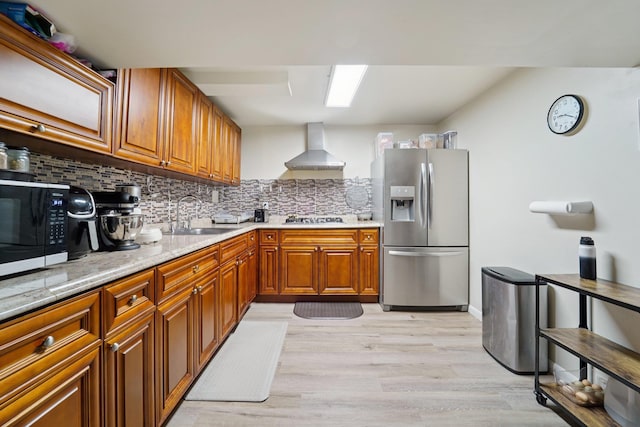 30 Birchwood Ter, Nanuet, NY 10954 - kitchen featuring appliances with stainless steel finishes, wall chimney range hood, brown cabinetry, decorative backsplash, and light wood-style floors