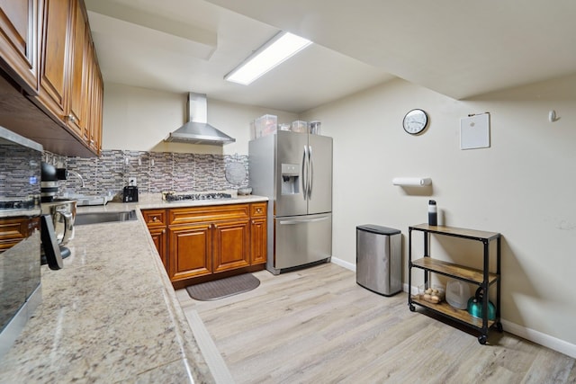 30 Birchwood Ter, Nanuet, NY 10954 - kitchen featuring appliances with stainless steel finishes, wall chimney exhaust hood, brown cabinets, backsplash, and light wood-style floors
