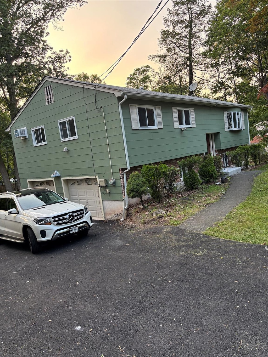 402 Kings Hwy, Valley Cottage, NY 10989 - property exterior at dusk featuring a garage, asphalt driveway, and a wall mounted AC