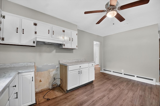 11 Tribune Ln, Red Hook, NY 12571 - kitchen featuring a baseboard heating unit, under cabinet range hood, a ceiling fan, wood finished floors, and white cabinetry