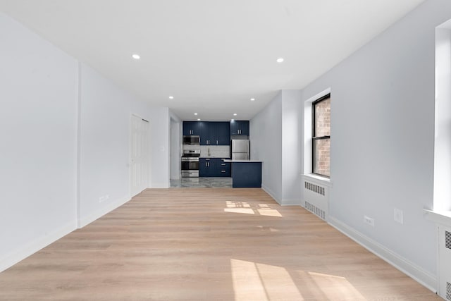 37-56 87th St Unit 3C, Jackson Heights, NY 11372 - unfurnished living room with radiator heating unit, light wood-style flooring, and recessed lighting