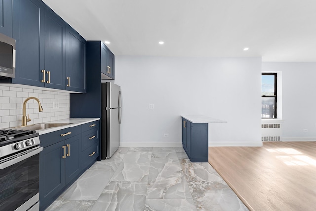 37-56 87th St Unit 3C, Jackson Heights, NY 11372 - kitchen with radiator, stainless steel appliances, blue cabinetry, light countertops, and tasteful backsplash