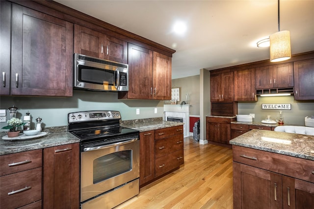 48 Devon Rd, Patterson, NY 12563 - kitchen with stainless steel appliances, light wood finished floors, dark stone counters, pendant lighting, and under cabinet range hood