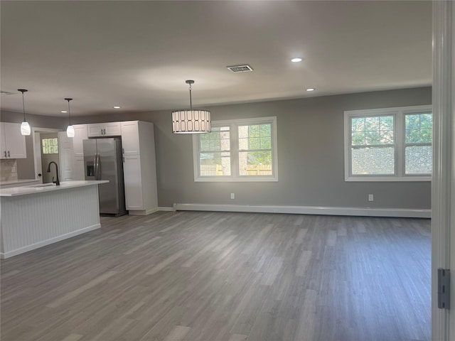 882 Union Blvd, West Islip, NY 11795 - kitchen featuring stainless steel refrigerator with ice dispenser, wood finished floors, light countertops, recessed lighting, and white cabinets