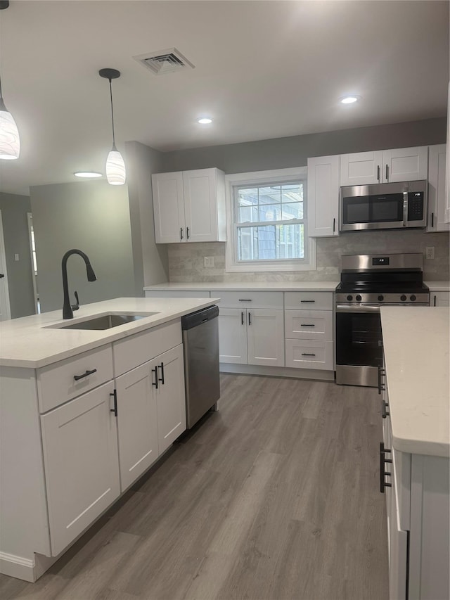 882 Union Blvd, West Islip, NY 11795 - kitchen featuring appliances with stainless steel finishes, light wood finished floors, tasteful backsplash, white cabinets, and light countertops