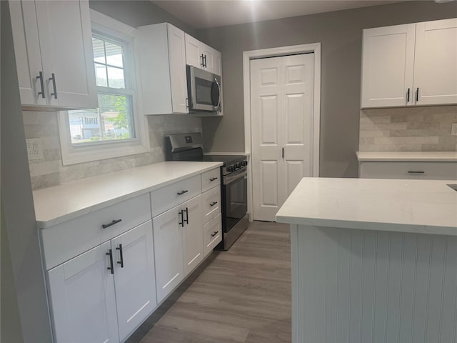 882 Union Blvd, West Islip, NY 11795 - kitchen featuring appliances with stainless steel finishes, white cabinetry, decorative backsplash, and wood finished floors
