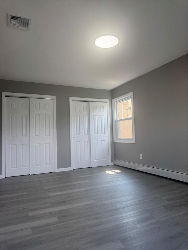 882 Union Blvd, West Islip, NY 11795 - unfurnished bedroom with two closets, baseboard heating, and wood finished floors