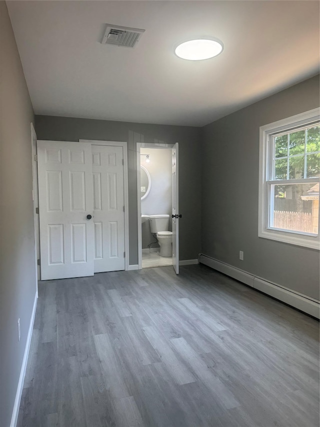 882 Union Blvd, West Islip, NY 11795 - unfurnished bedroom featuring baseboard heating, wood finished floors, and ensuite bath