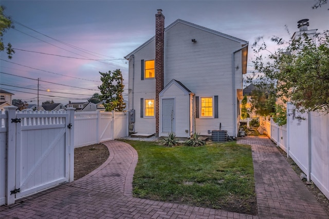 1859 George Ct, Merrick, NY 11566 - back of property at dusk featuring a gate, a fenced backyard, and a chimney