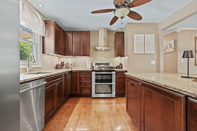 39 Bykenhulle Rd, Hopewell Junction, NY 12533 - kitchen with wall chimney exhaust hood, appliances with stainless steel finishes, light wood-style floors, light stone counters, and decorative backsplash
