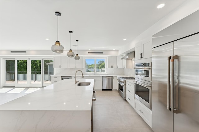 141 Flamingo St, Atlantic Beach, NY 11509 - kitchen featuring high quality appliances, tasteful backsplash, white cabinetry, light stone countertops, and a large island with sink
