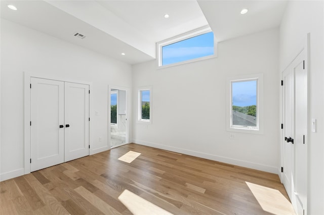 141 Flamingo St, Atlantic Beach, NY 11509 - unfurnished bedroom with a towering ceiling, light wood-style flooring, connected bathroom, and recessed lighting