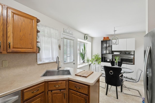 27 Primrose Ln, North Babylon, NY 11703 - kitchen featuring stainless steel appliances, light countertops, a peninsula, and brown cabinetry